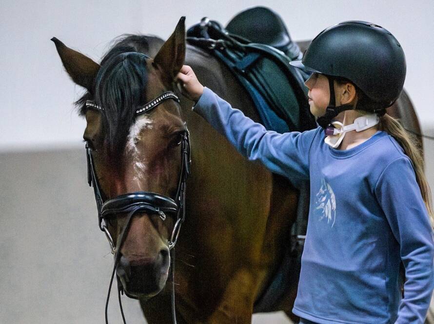 Ein Mädchen das ein Pferd longiert.