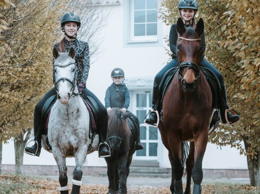 Drei Mädchen reiten auf ihren Pferden und haben Spaß.
